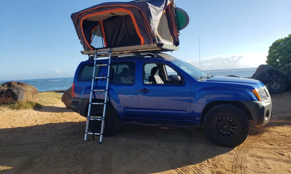 Blue Xterra 4x4 camper in Makawao, Hawaii, with a premium hardtop rooftop tent and camping gear included. This 15-foot camper sleeps up to 4 guests with a full-size bed, accommodates up to 5 passengers, has a 4.7-star rating from 199 trips, offers delivery within 15 miles, includes unlimited mileage, and is not pet-friendly.