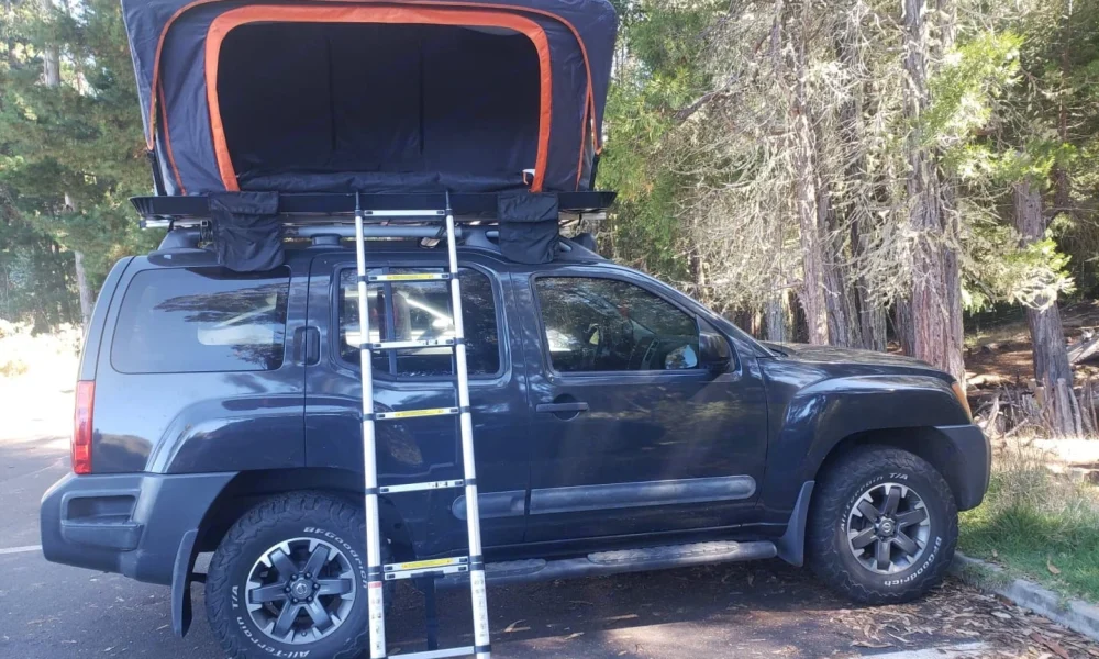 Dark Grey Xterra 4x4 truck camper in Makawao, Hawaii, with a premium rooftop tent and camping gear included. This 15-foot camper sleeps up to 4 guests with a full-size bed, accommodates up to 5 passengers, has a 5.0-star rating from 64 trips, offers delivery within 15 miles, includes unlimited mileage, and is not pet-friendly.