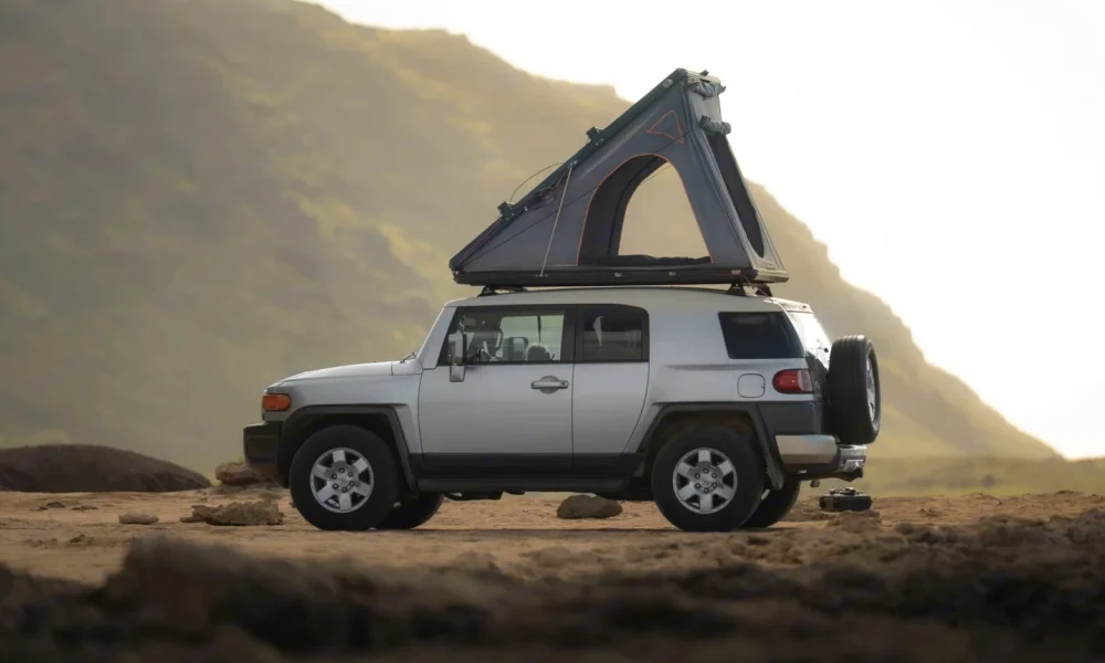 Toyota FJ Surf Cruiser rooftop tent camper in Honolulu, Hawaii. This 16-foot camper sleeps 2 guests with a queen-size bed, accommodates up to 5 passengers, has a 5.0-star rating from 28 trips, offers delivery within 25 miles, includes unlimited mileage and unlimited generator hours, and is not pet-friendly.